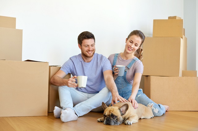 happy couple with boxes and dog moving to new home