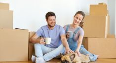 happy couple with boxes and dog moving to new home