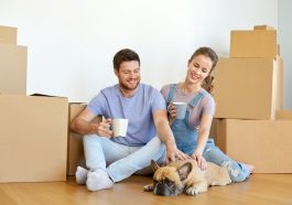 happy couple with boxes and dog moving to new home